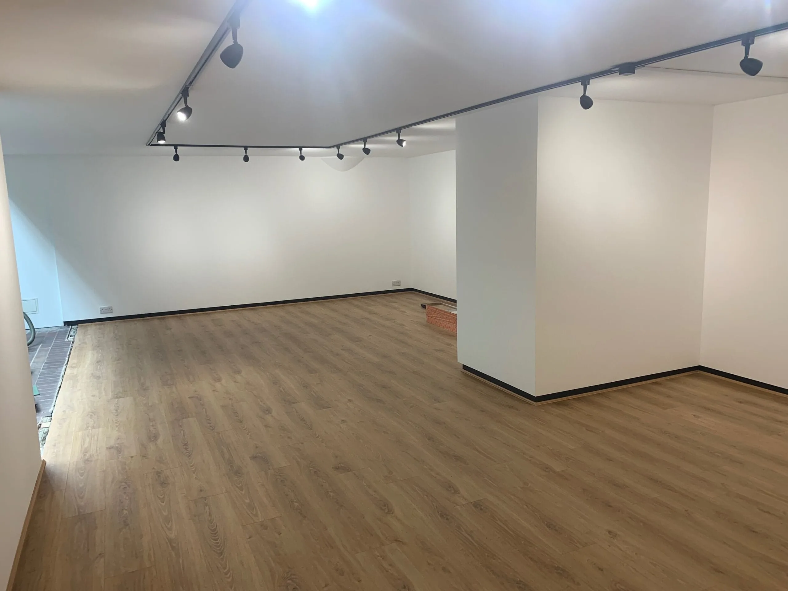 a room with a wooden floor and a ceiling light and all white painted walls